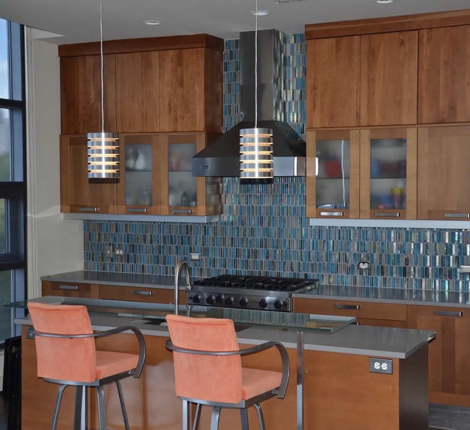 Kitchen bar with peach bar chairs overlooking a beautiful blue/teal/dark kitchen backsplash.
